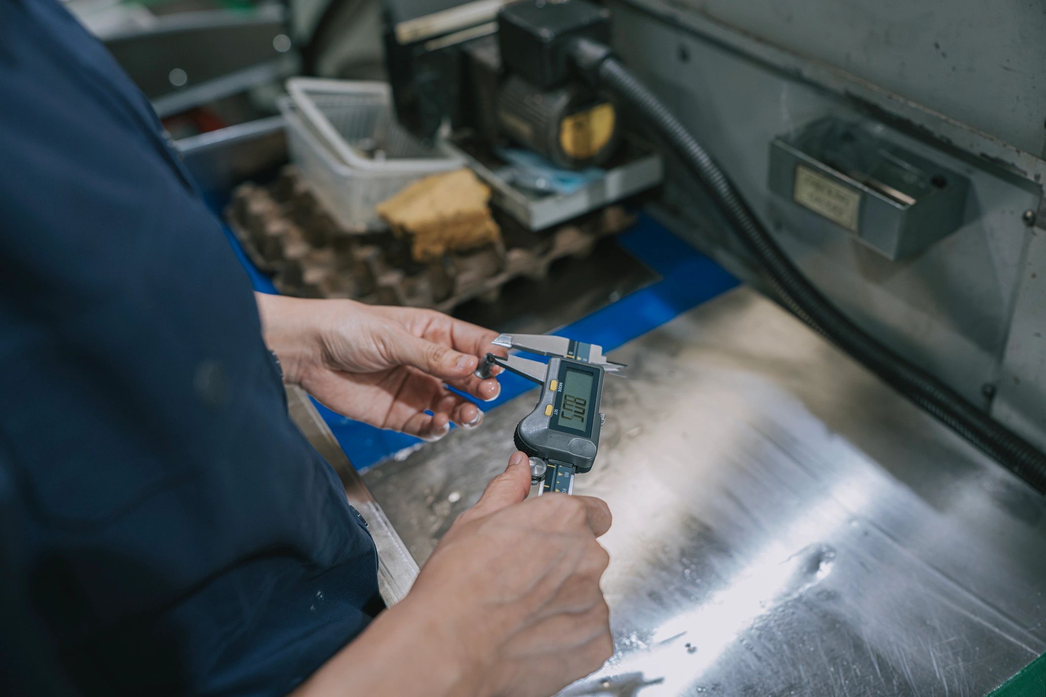 Technician measuring parts with a digital caliper in a factory